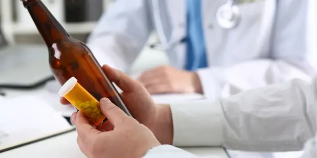 доктор держит в руках бутылку и таблетки